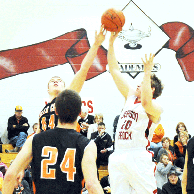 Tiger senior Reese Hogue rises up and denies the shot attempt of Johnson-Brock’s Sean Koperski (eventually corralled by Jack Hartman, bottom left) during the 1st quarter of the eighth-ranked Tigers 66-37 road victory last Thursday. Photo by Jim Langan.