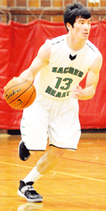 Irish junior Austin Malone pushes the ball up the court Saturday night during the A Division championship game of the 85th annual MUDECAS tournament in Beatrice. Malone scored 15 team-high points in Sacred Heart's loss to Freeman. Photo by Jim Langan.