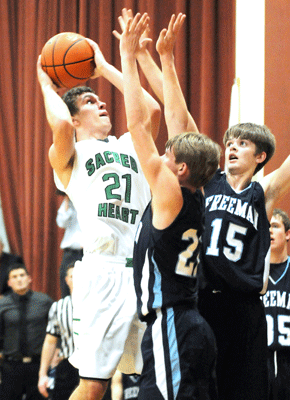 FC Sacred Heart senior Matt Goltz finishes a tough shot in traffic over Freeman’s Isaac Frerichs and Holden Scott during the 2nd quarter of Saturday’s A Division MUDECAS Championship at Beatrice. Photo by Jim Langan.  