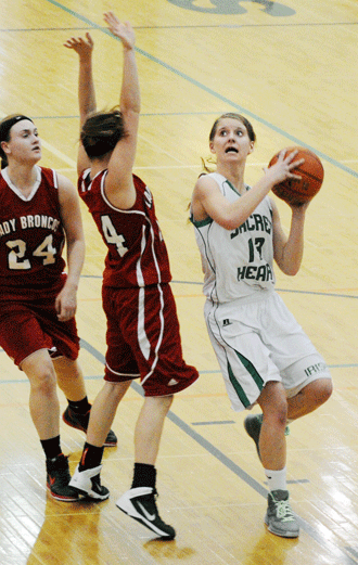Sacred Heart junior Elizabeth Magdanz drives around Wauneta-Palisade's Brianna Einspahr for two of her game-high 12 points as part of the Lady Irish's 45-25 victory Thursday morning. Magdanz scored 9 of her 12 points in the first half of the Class D-2 first-round game at Lincoln Southwest. Photo by Jason Schock. 
